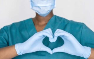 A nurse in scrubs showing Proposal Support by making a heart shape with her hands.