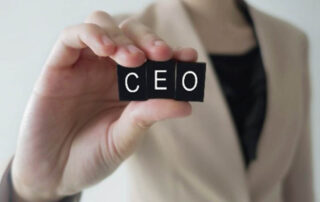 A woman holding up a block with the word ceo on it, demonstrating her success as a prominent figure in the business world.